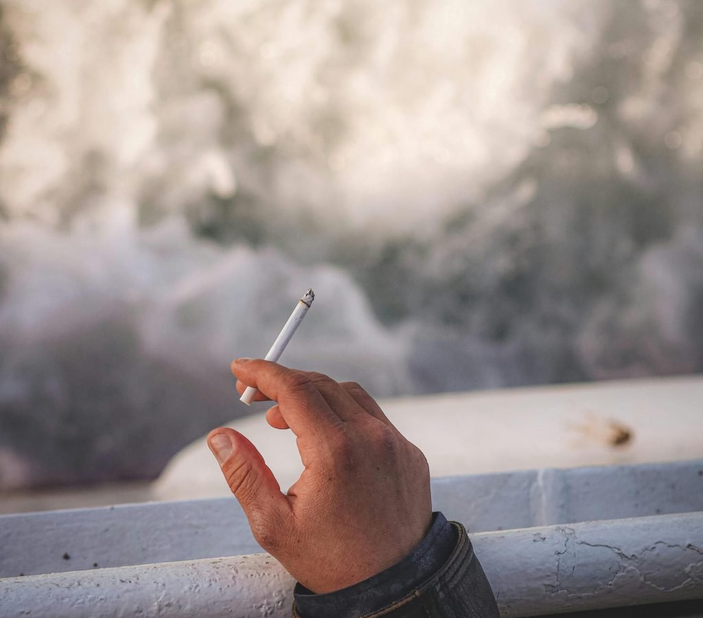 A person holding a cigarette with ocean waves in the background, captured in İstanbul, Turkey.